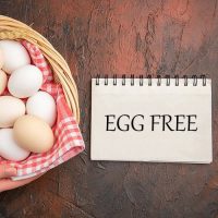 top-view-white-chicken-eggs-inside-basket-with-towel-dark-table